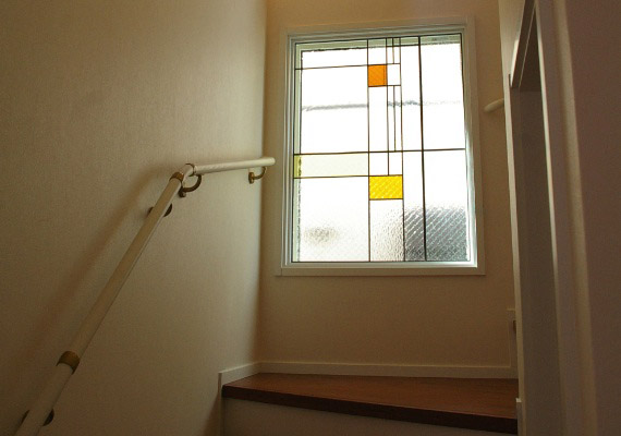ステンドグラス；階段室吹抜けFIX窓<br>透明系と落ち着いた色ガラスを織り交ぜて制作した上質なステンドグラス。<br>日々の暮らしの中に光を透した感動が続くシンプルなデザイン。